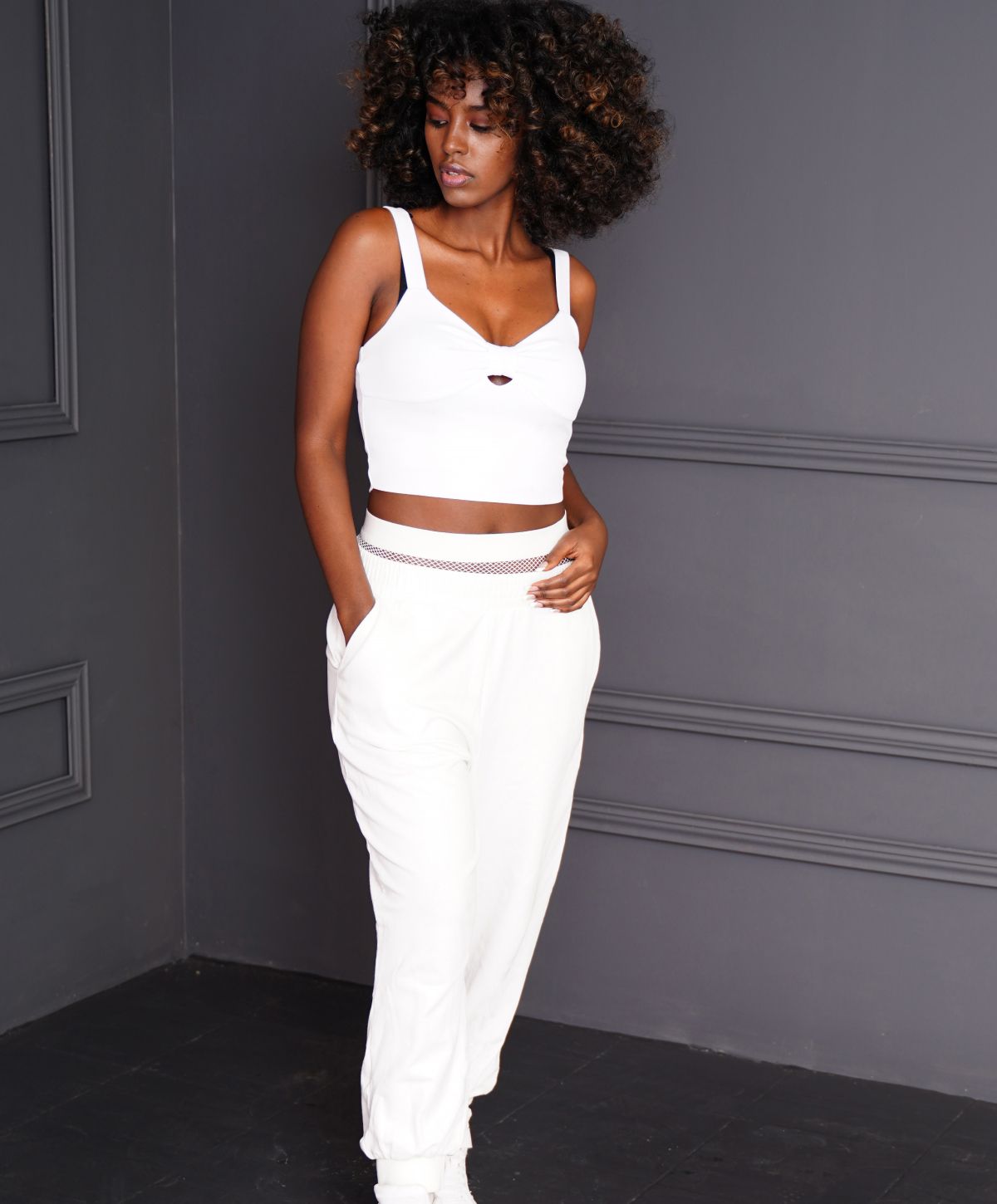 Model in white outfit against gray background.