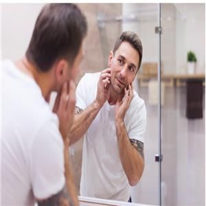 Man inspecting his skin in bathroom mirror.