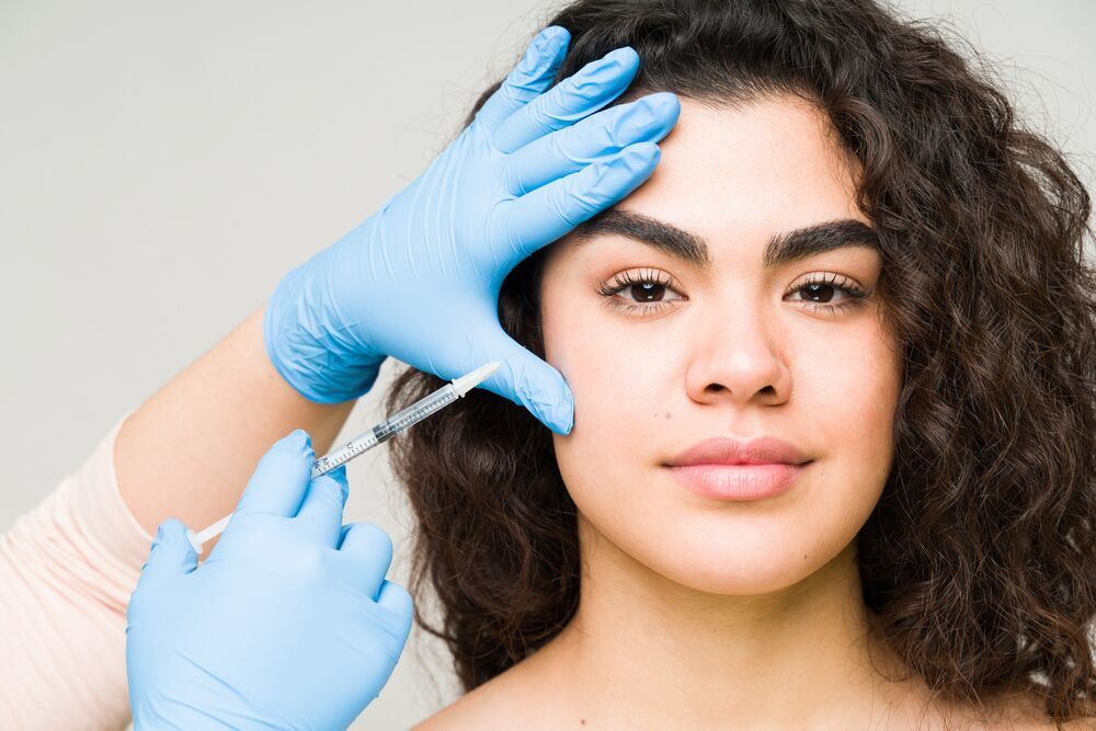 Woman receiving facial injection from healthcare professional.