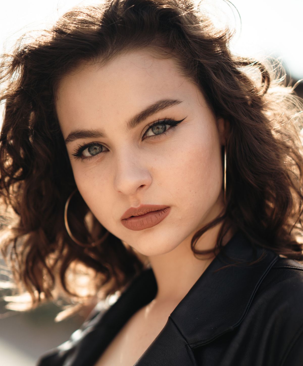 Young woman with curly hair and bold makeup.