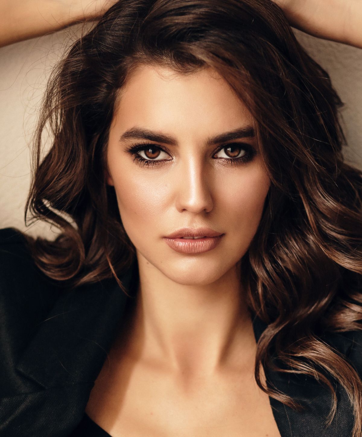 Woman smiling on a bed, sunlight streaming in.