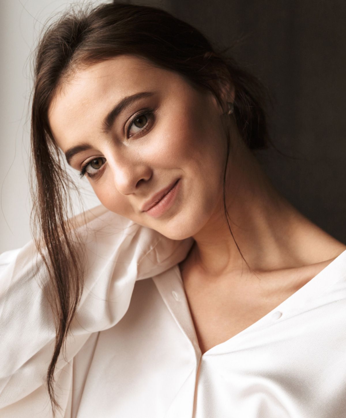 Smiling woman in a white blouse, soft lighting.