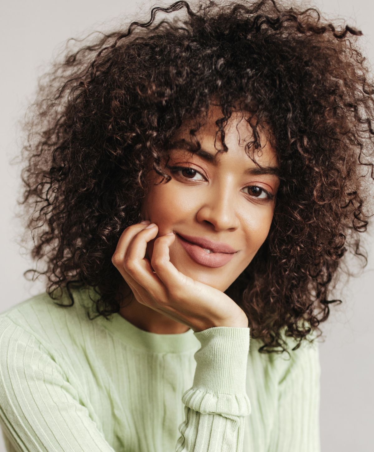 Woman with curly hair, smiling softly.