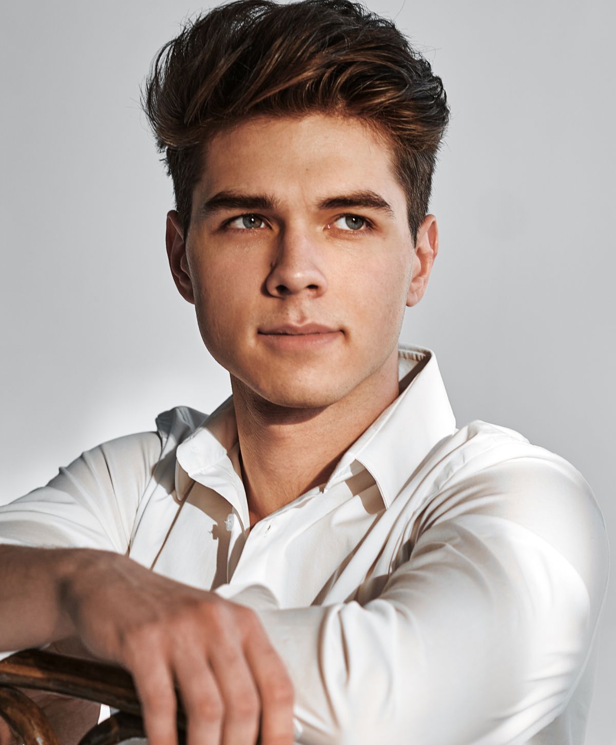 Young man in a white shirt, thoughtful expression.
