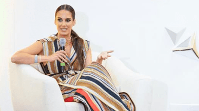 Woman speaking at event, wearing striped dress.