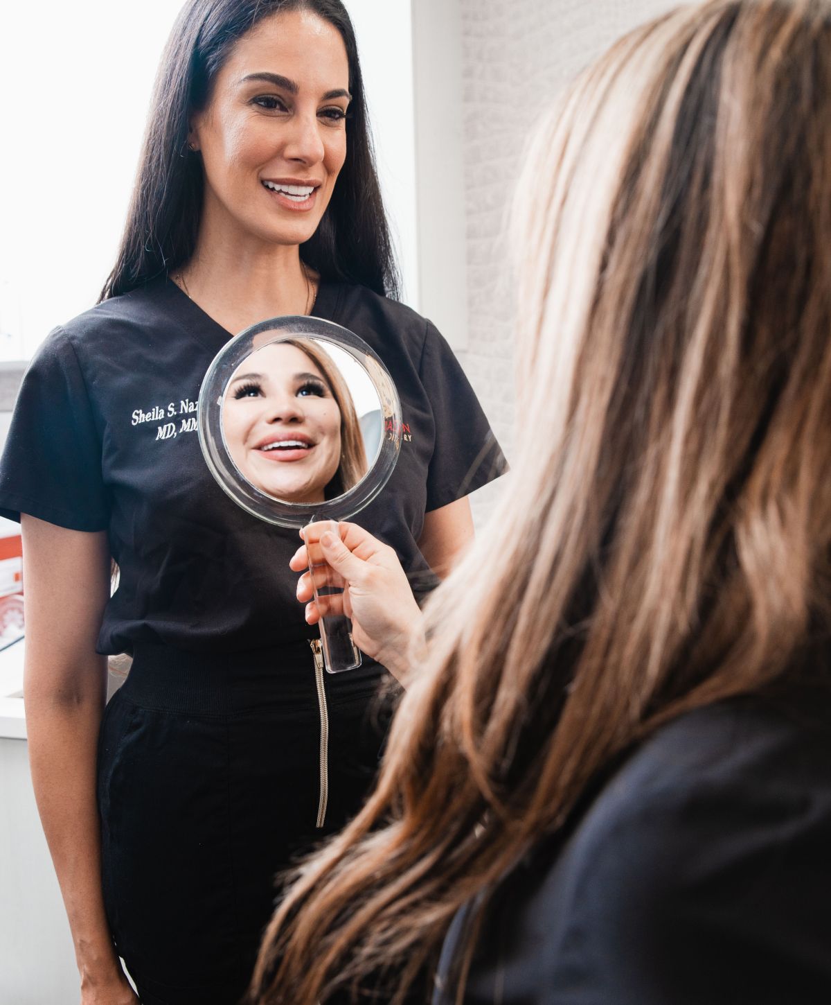 Two women discussing beauty in a mirror.