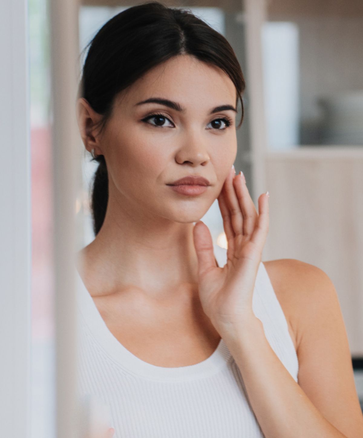 Woman touching her face, looking contemplative.