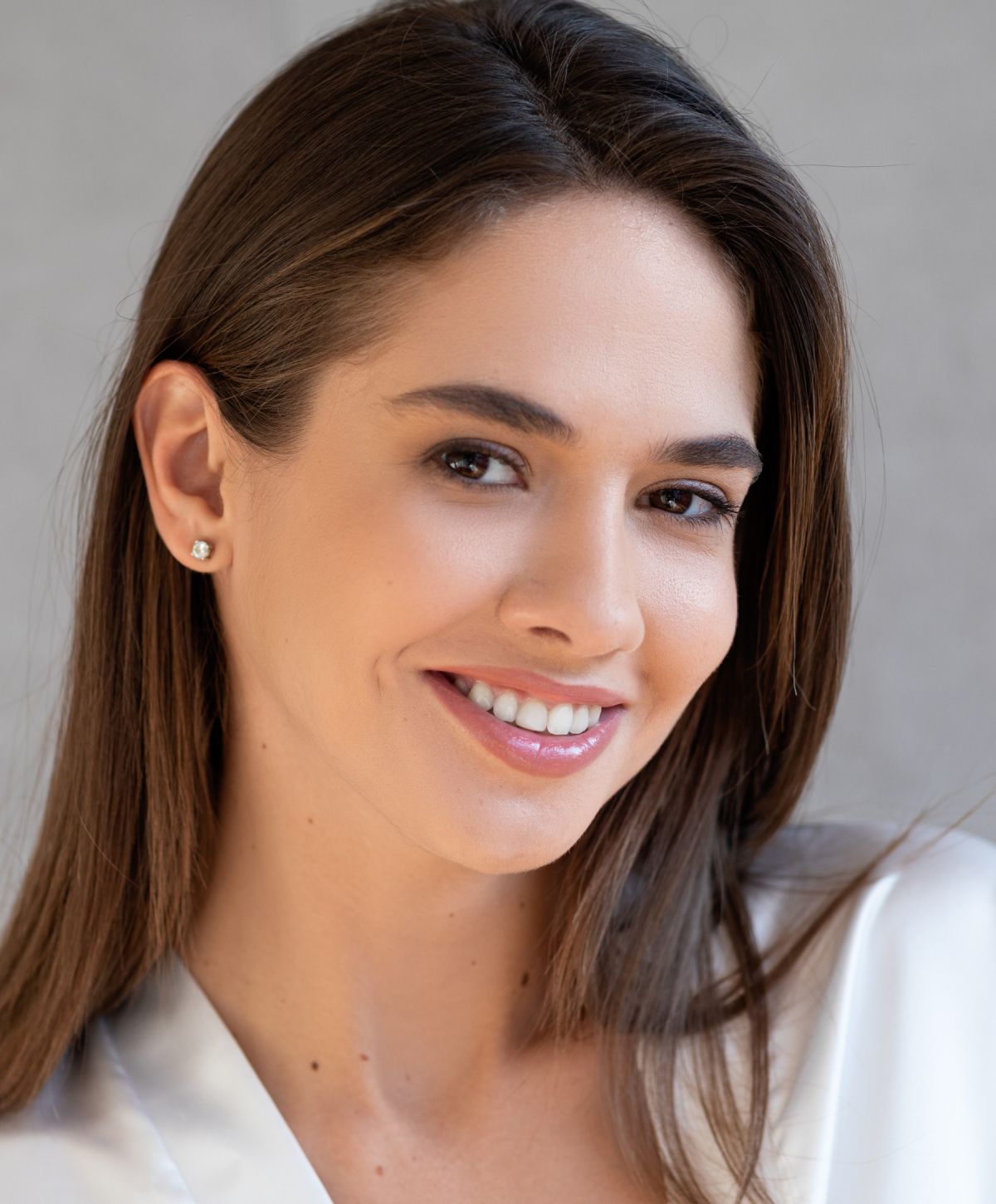 Smiling woman with long hair and earrings.