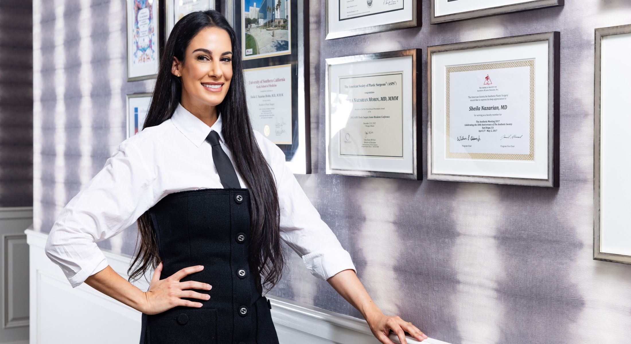 Professional woman standing next to framed certificates.