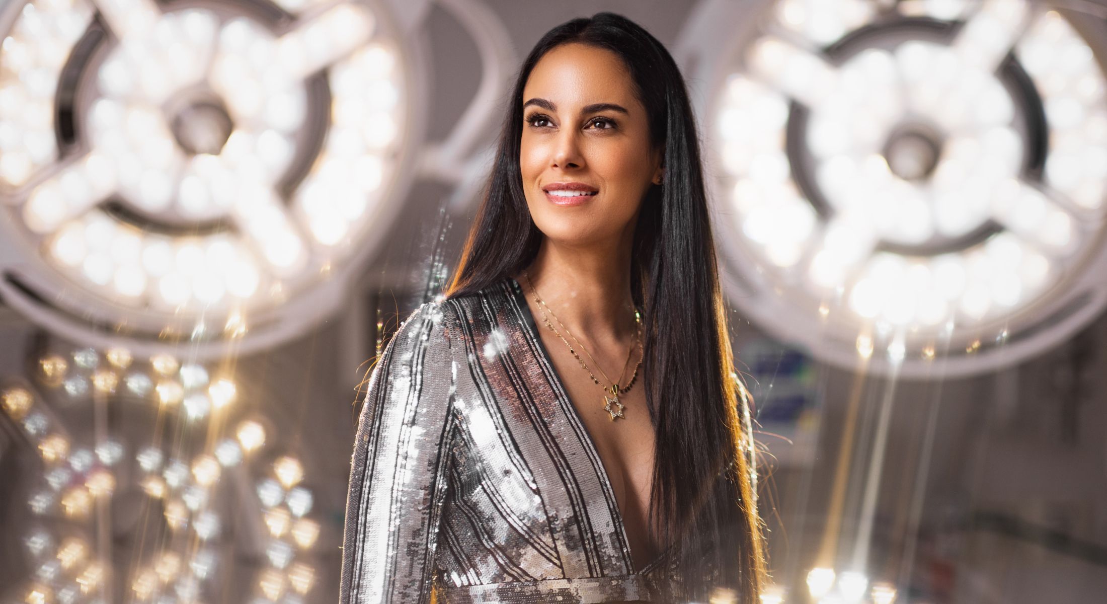 Woman in shimmering dress against bright background.