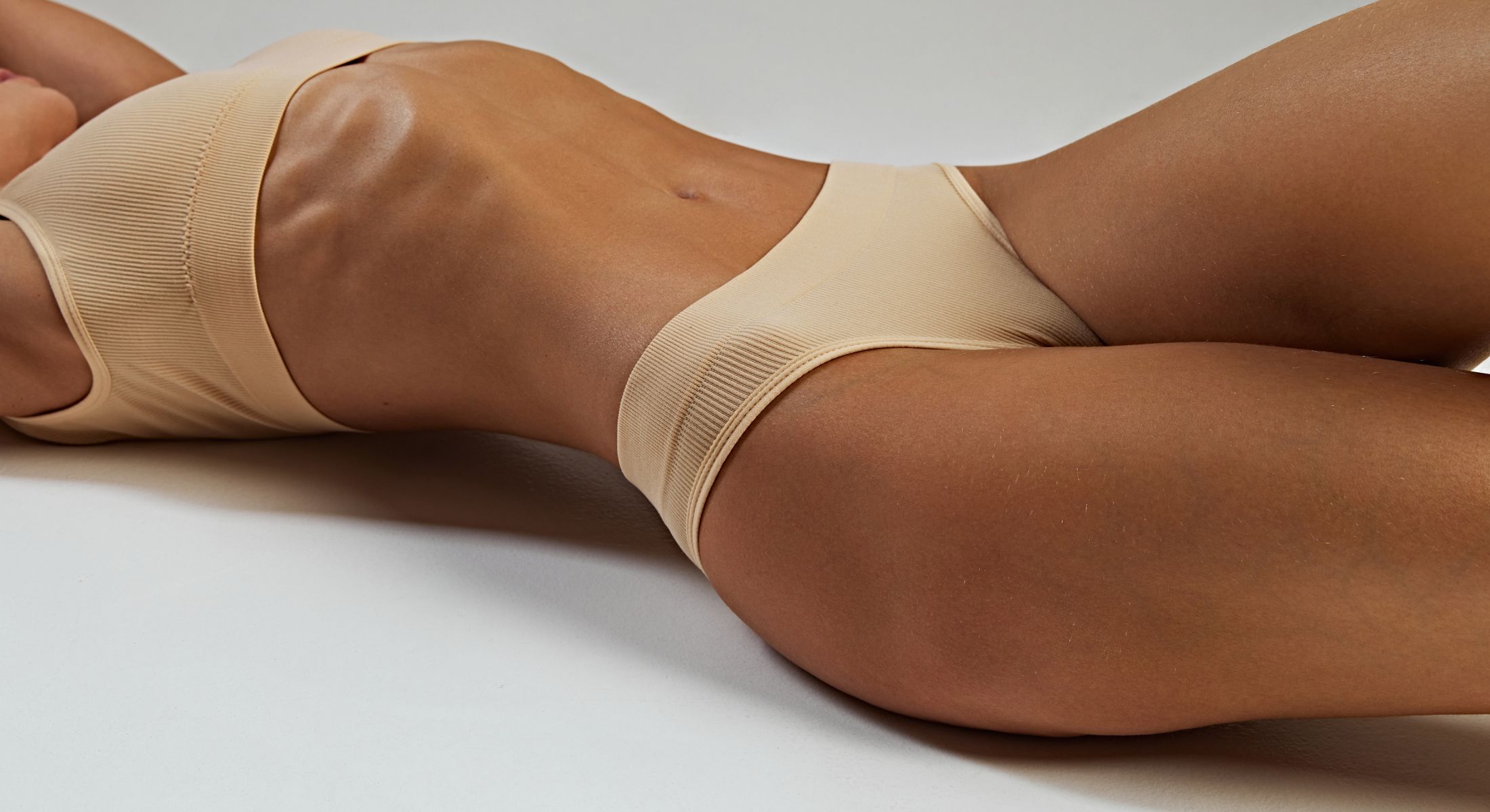 Athletic figure in neutral-toned activewear, lying down.