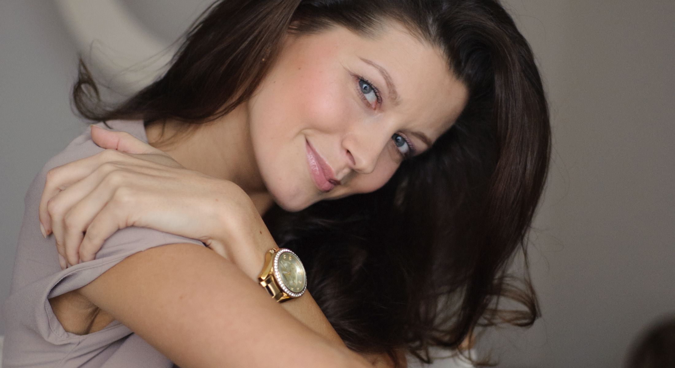 Smiling woman with long hair and watch.