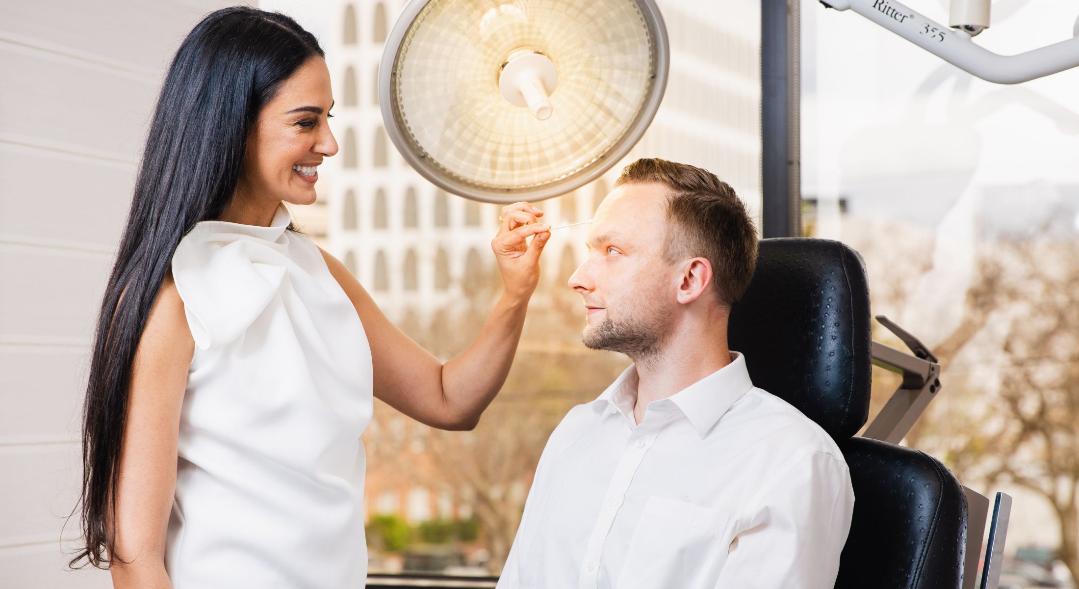 Practitioner preparing male patient for treatment.