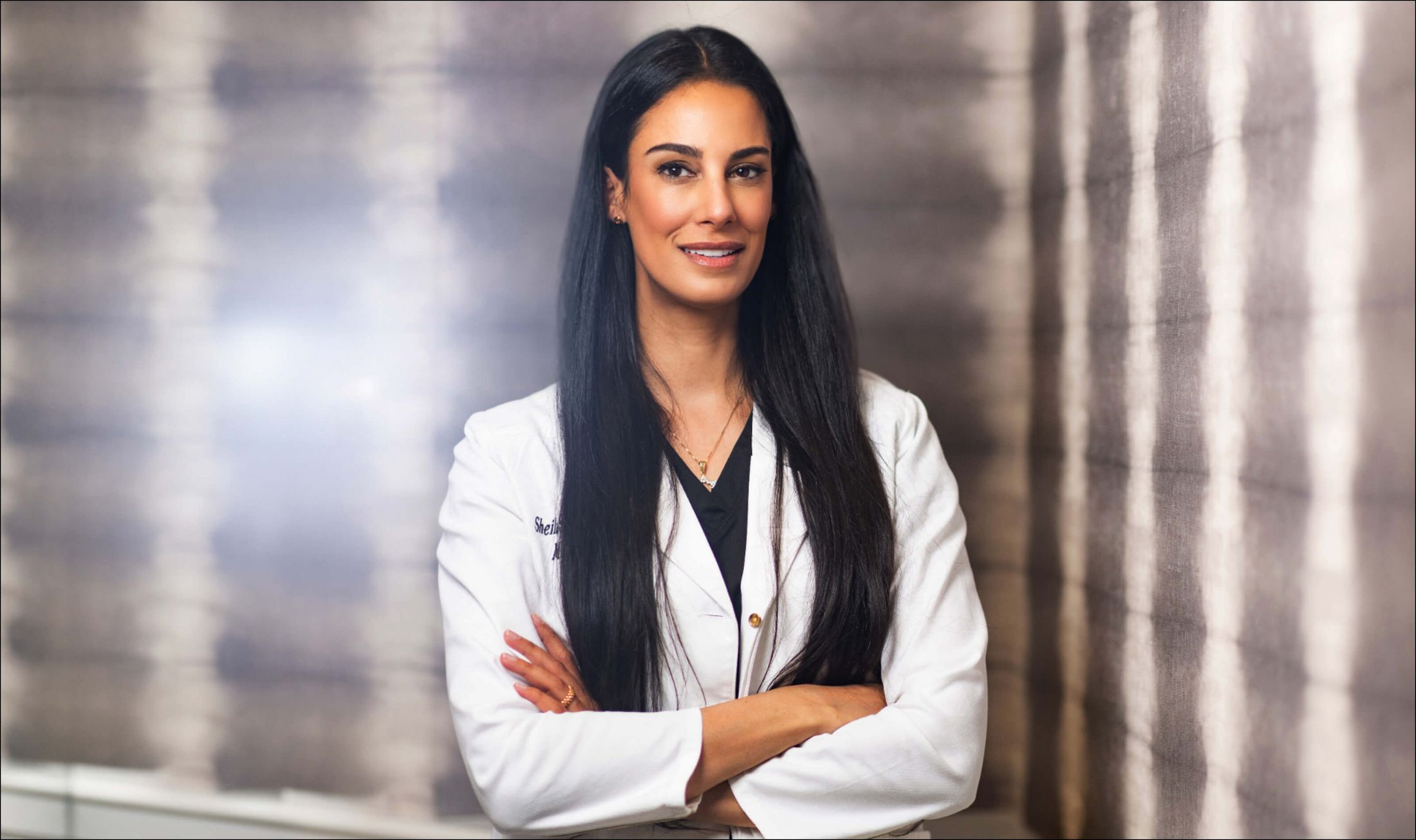 Female doctor in white coat, smiling confidently.