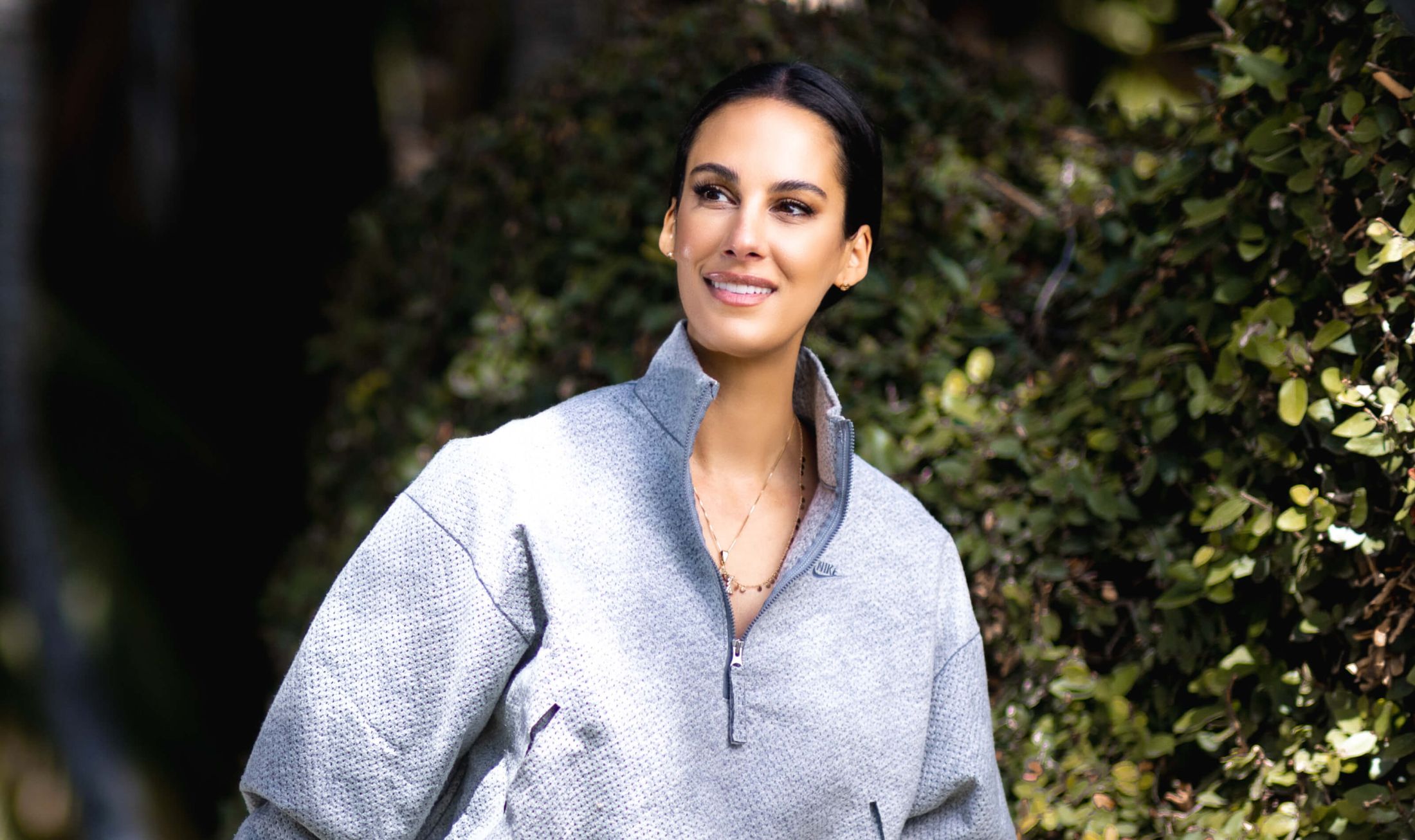 Smiling person in a casual gray sweatshirt outdoors.